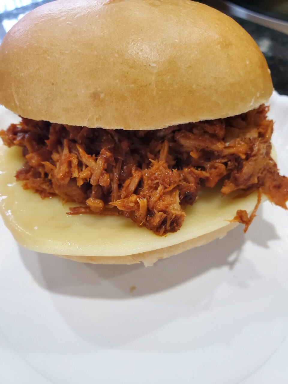 Delicious pulled pork on a fresh bun with provolone cheese